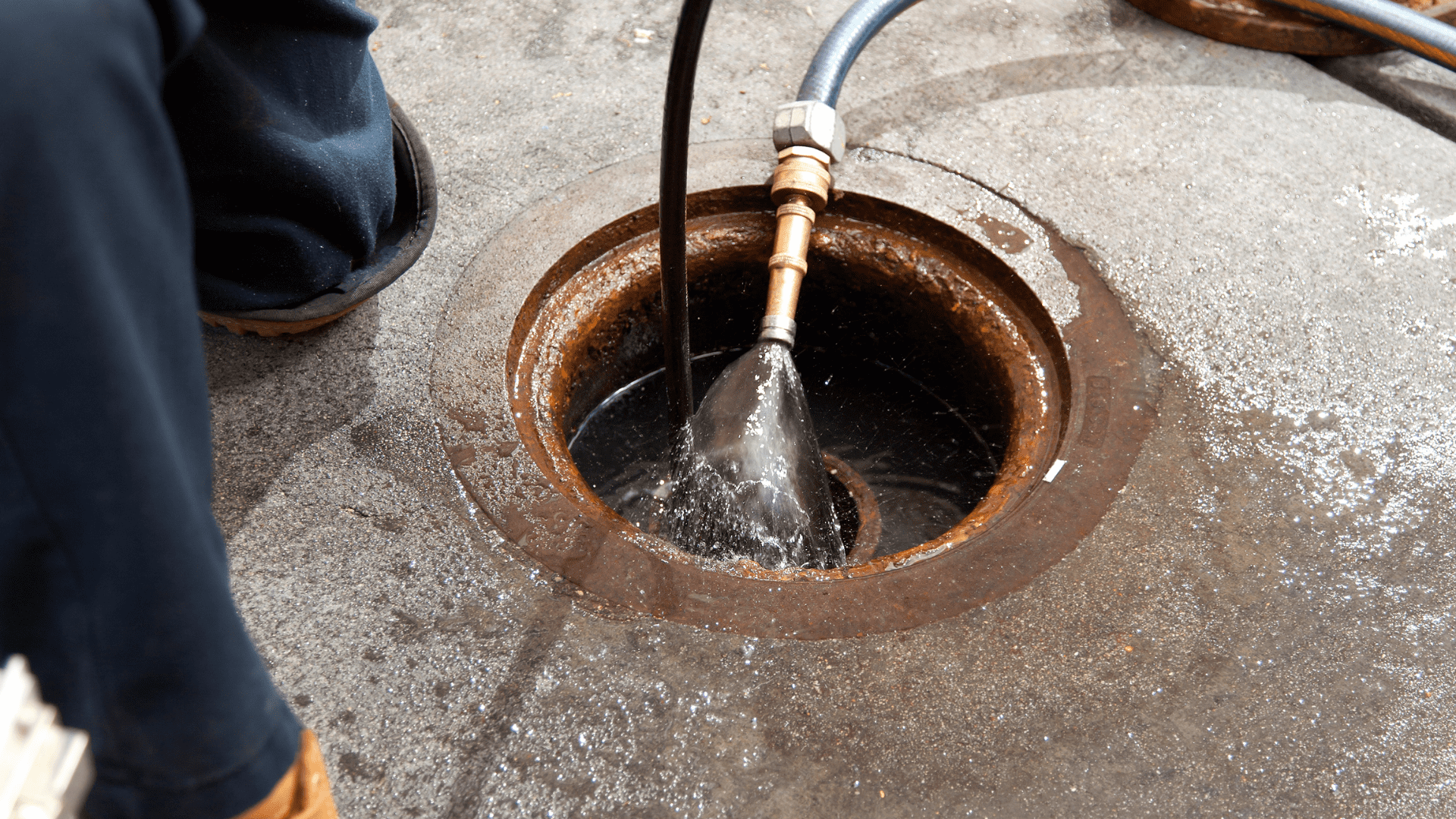 Trabajador utilizando un chorro de agua a alta presión para limpiar una alcantarilla de Plomería ESM servicios en San Sebastián.